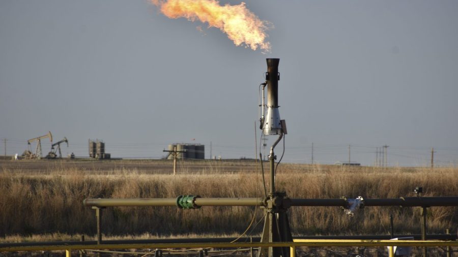 A flare for burning excess methane, or natural gas, from crude oil production, is seen at a well pad east of New Town, N.D., May 18, 2021. (AP Photo/Matthew Brown, File)