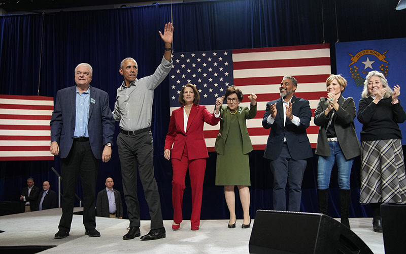 Nevada Gov. Steve Sisolak (D) and former President Obama stand on stage