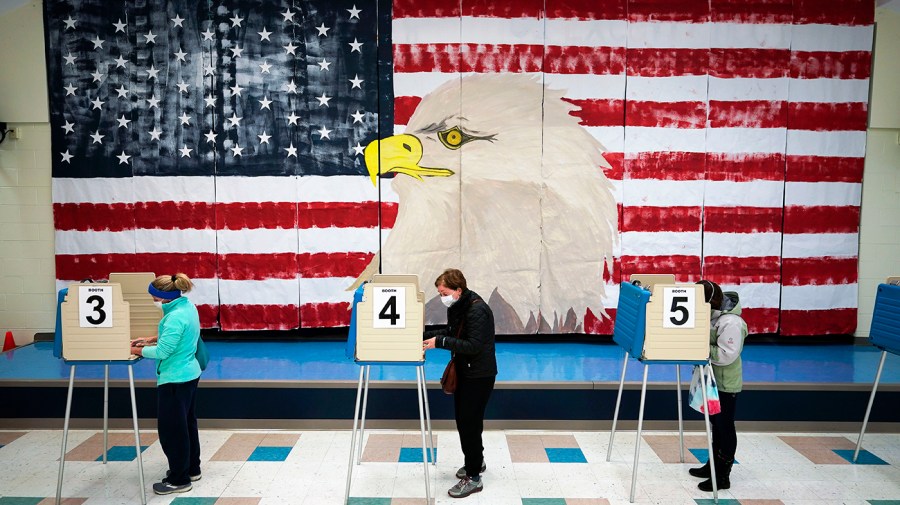 Voters cast their ballots under a giant mural