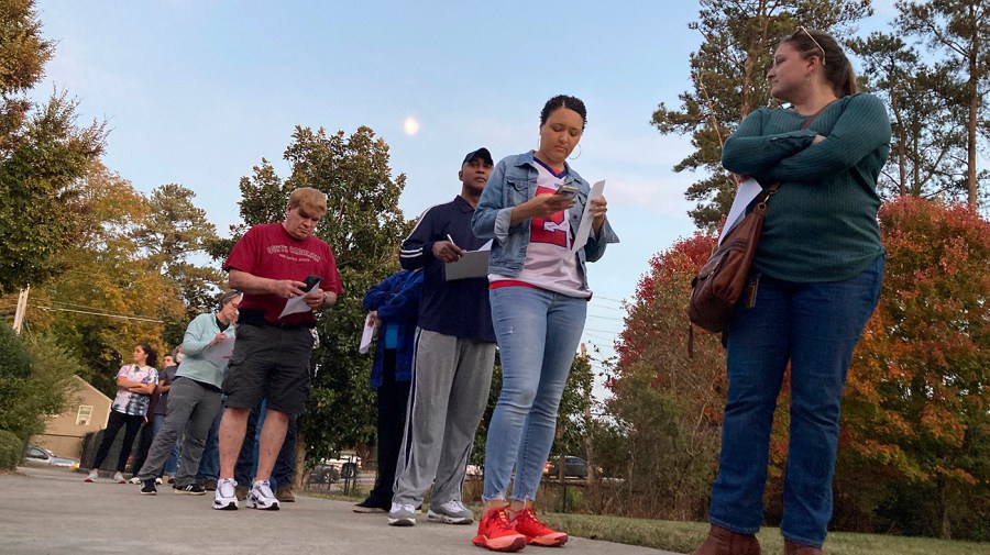 Voters fill out forms as they wait in line to cast ballots