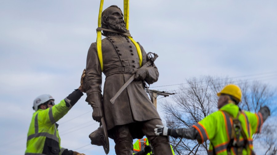 Workers begin to lay the bronze statue of Confederate General A.P. Hill onto a flatbed truck