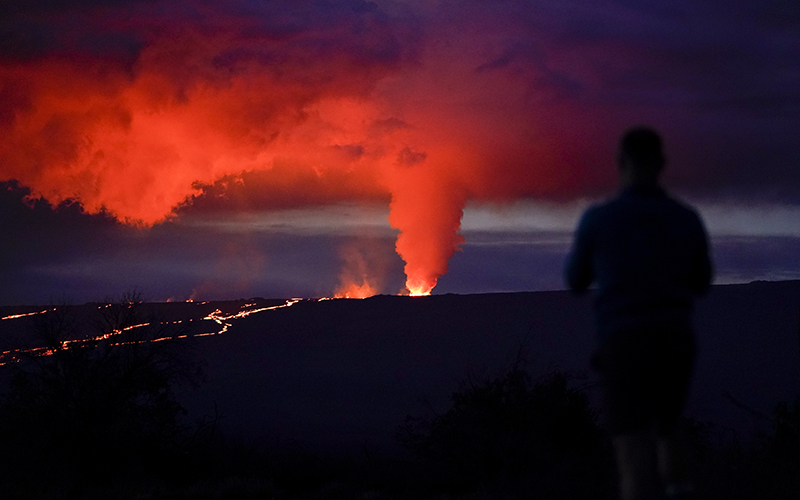 A man looks on as lava erupts from the Mauna Loa volcano