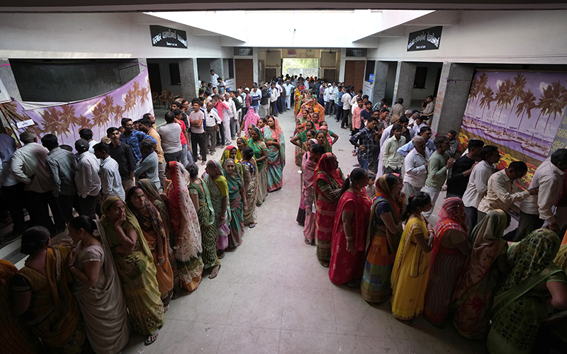 People stand in queue to cast their votes in Wadhwan, India