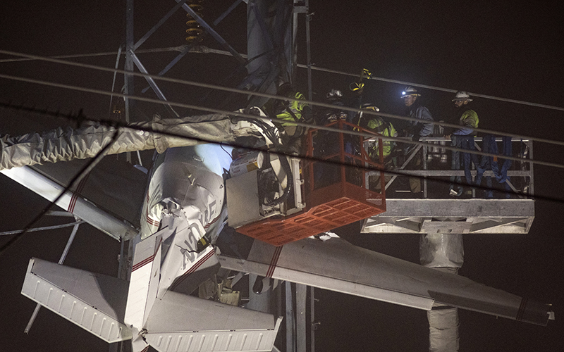 First responders work to rescue aircraft passengers after the small plane crashed and became stuck in live power lines