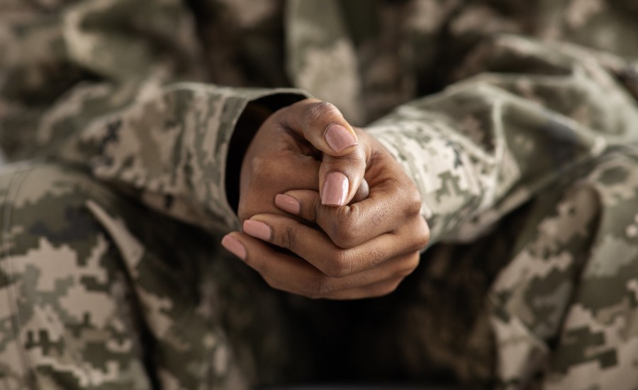 Person in camouflage holding hands.