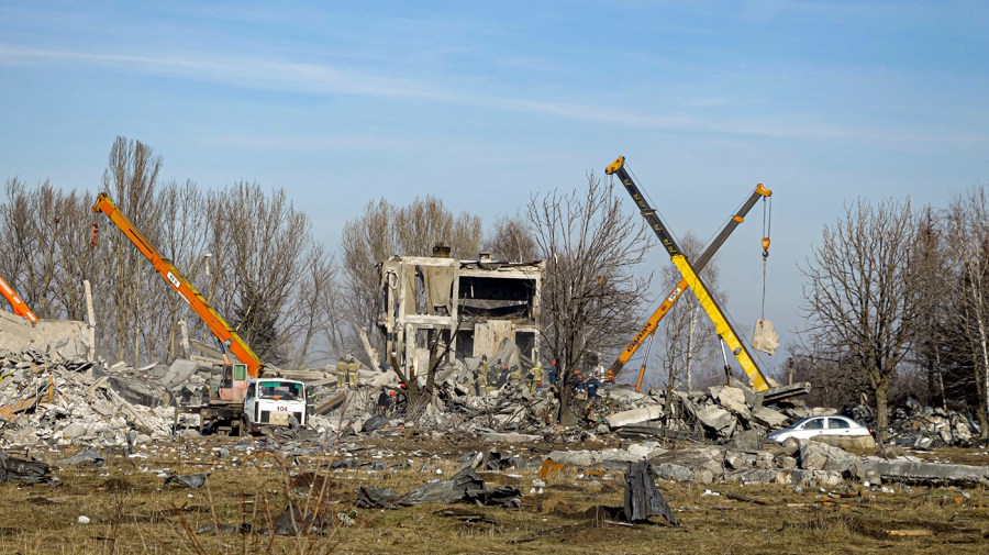 Workers clean rubbles after Ukrainian rocket strike under a blue sky