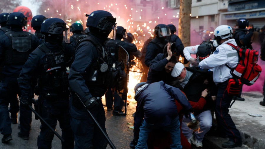 Activists protect themselves against riot police officers