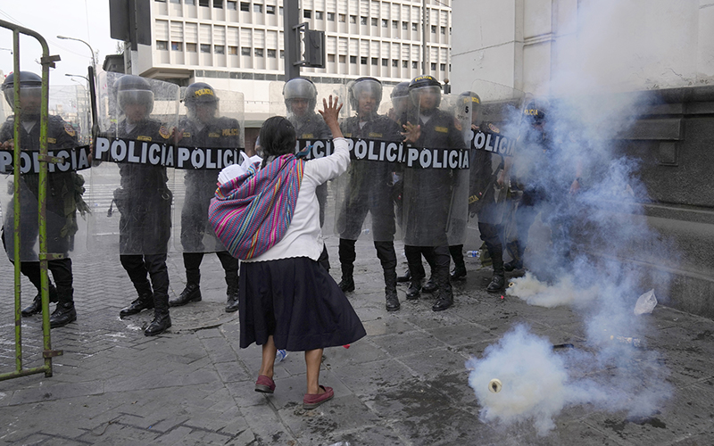 A woman tries to hold back police during protests in Peru