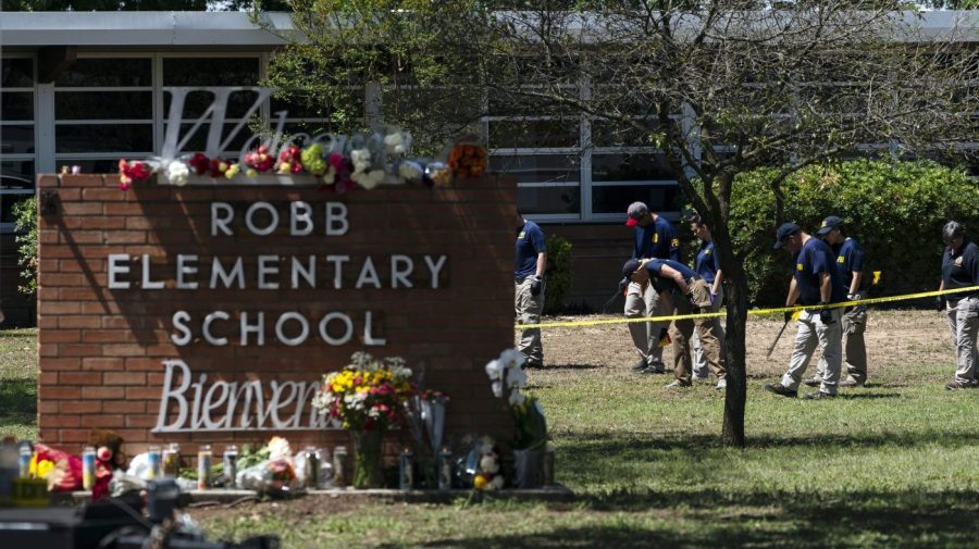 Flowers and candles adorn a sign at Robb Elementary School, the site of a mass shooting in 2022.