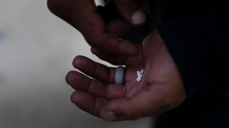 A homeless addict holds pieces of fentanyl in Los Angeles