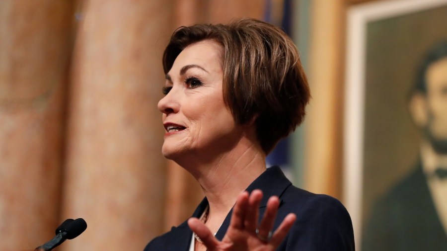 Kim Reynolds gestures while speaking into a microphone.