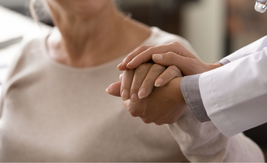 a doctor or nurse holding the hands of a female middle aged patient