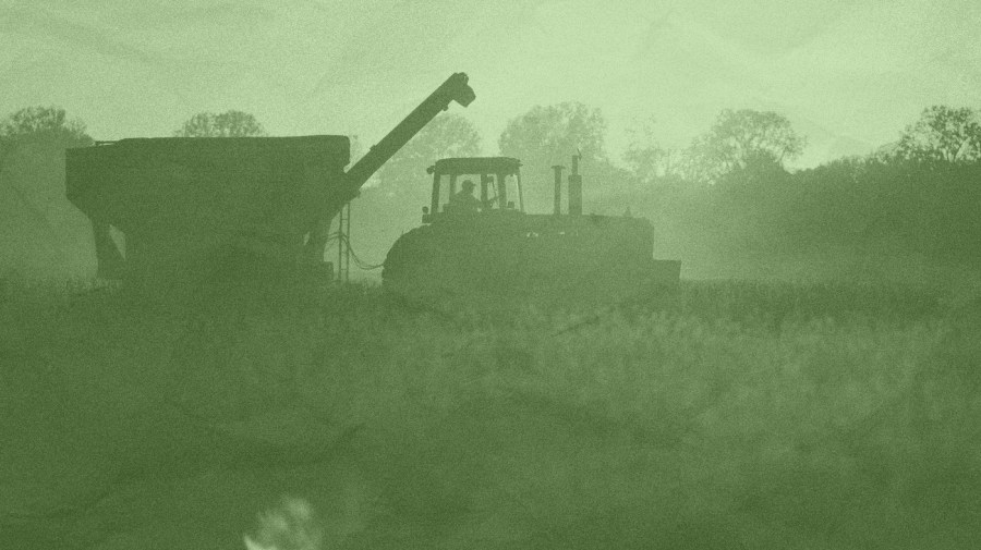 In a green-tinted picture, a farm vehicle is seen harvesting a field