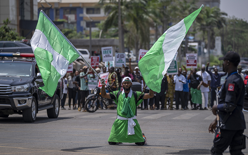 A demonstrator holds two Nigerian flags