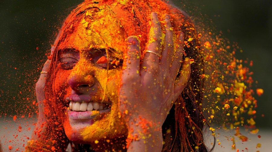 A man applies colored powder on his friend's face during celebrations marking Holi