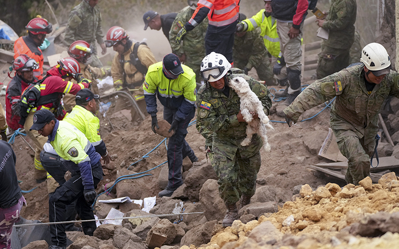 A soldier carries a dog found among the rubble of buildings destroyed by a deadly landslide that buried dozens of homes in Alausi, Ecuador