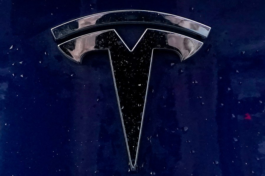 FILE - A Tesla electric vehicle emblem is affixed to a passenger vehicle Sunday, Feb. 21, 2021, in Boston. Tesla is dropping prices for the third time since late last year in an apparent effort to attract new buyers. The cuts range from $5,000 for slower-selling high-priced models to $1,000 at the low end of its price range. (AP Photo/Steven Senne, File)