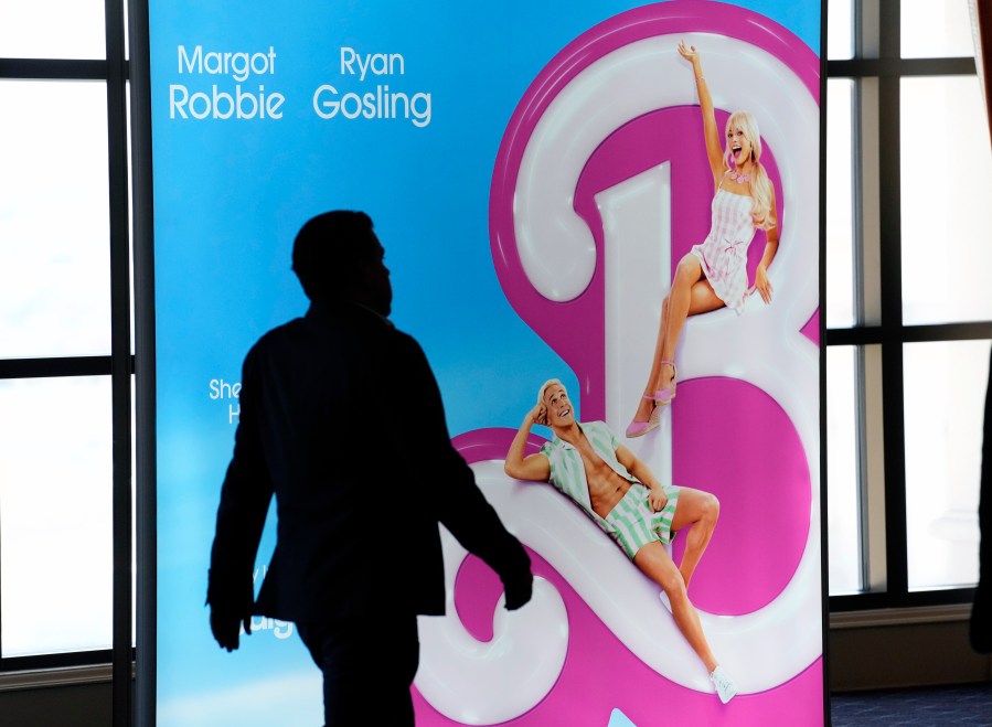 An attendee walks past an advertisement for the upcoming film "Barbie" on the opening day of CinemaCon 2023, the official convention of the National Association of Theatre Owners (NATO) at Caesars Palace, Monday, April 24, 2023, in Las Vegas.