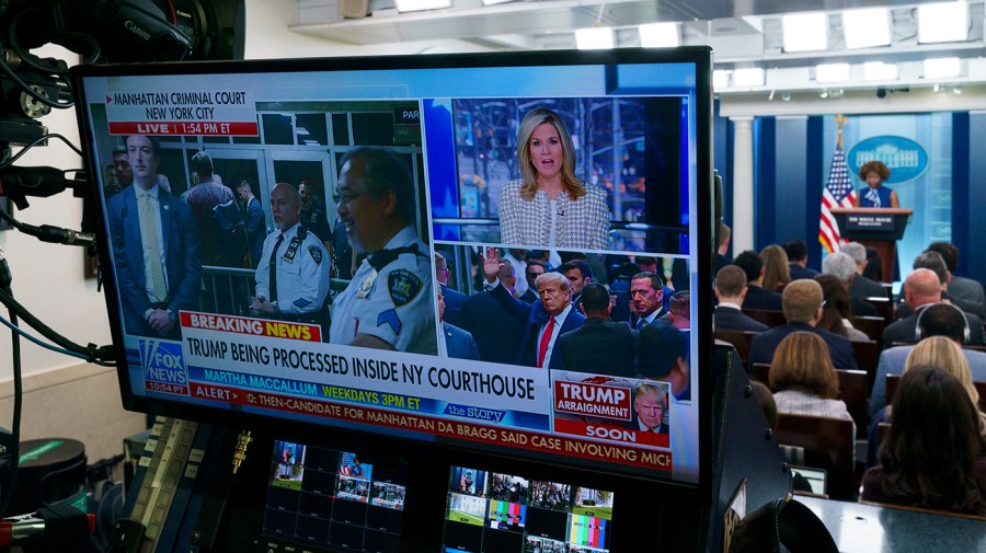 TV coverage of former President Trump heading to a New York courthouse is seen as White House press secretary Karine Jean-Pierre addresses reporters