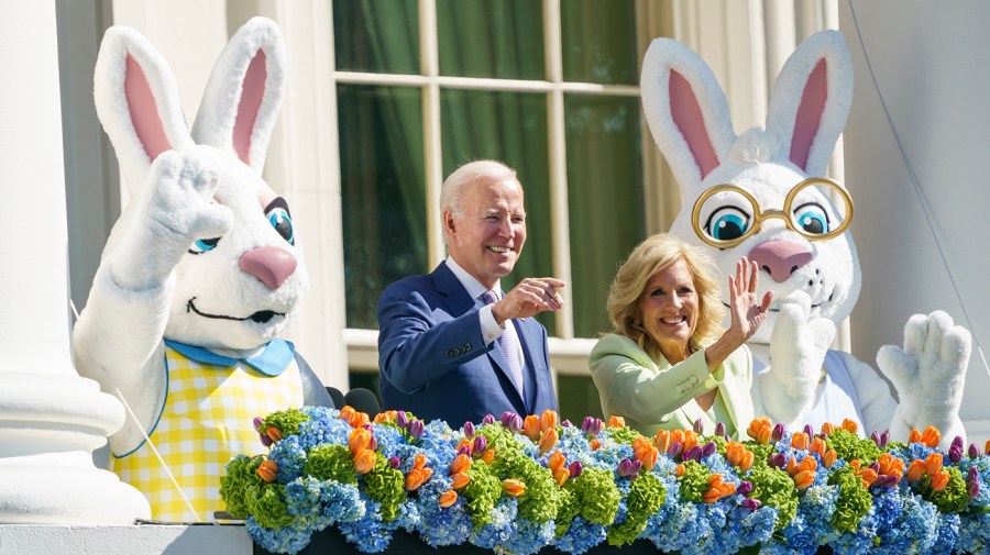 President Biden and first lady Jill Biden, flanked by two Easter Bunnies, wave from the White House balcony