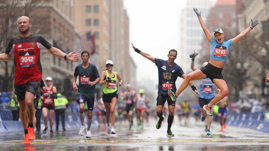 Brooke Lorentz jumps in celebration after crossing the finish line during the 127th Boston Marathon