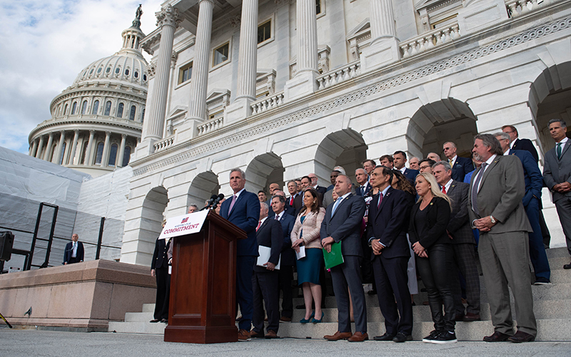 Speaker Kevin McCarthy (R-Calif.) speaks at a podium as members of his party stand on the steps behind him