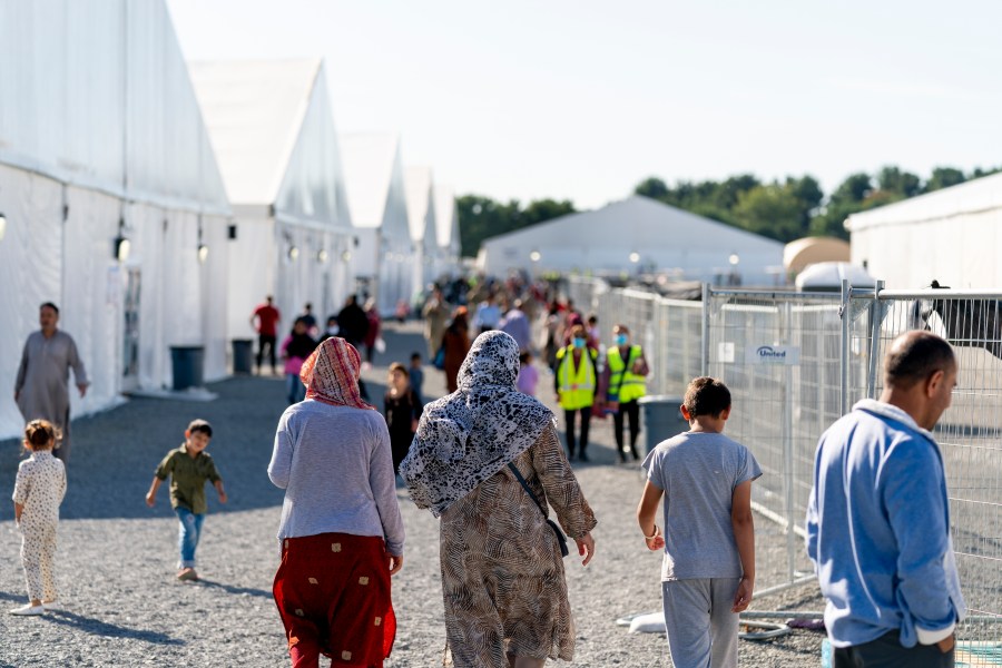 FILE - Afghan refugees walk through an Afghan refugee camp at Joint Base McGuire Dix Lakehurst, N.J., on Sept. 27, 2021.