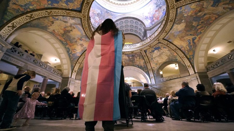 FILE - Glenda Starke wears a transgender flag as a counter protest during a rally in favor of a ban on gender-affirming health care legislation, March 20, 2023, at the Missouri Statehouse in Jefferson City, Mo. (AP Photo/Charlie Riedel, File)