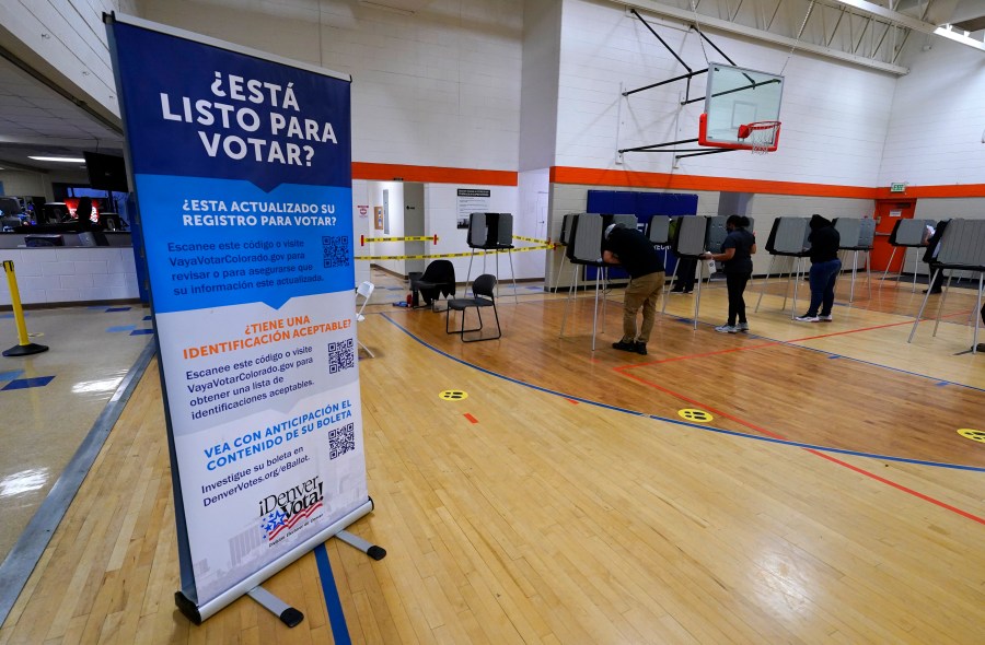 A sign in Spanish is displayed near voters as they cast their ballots at stations.