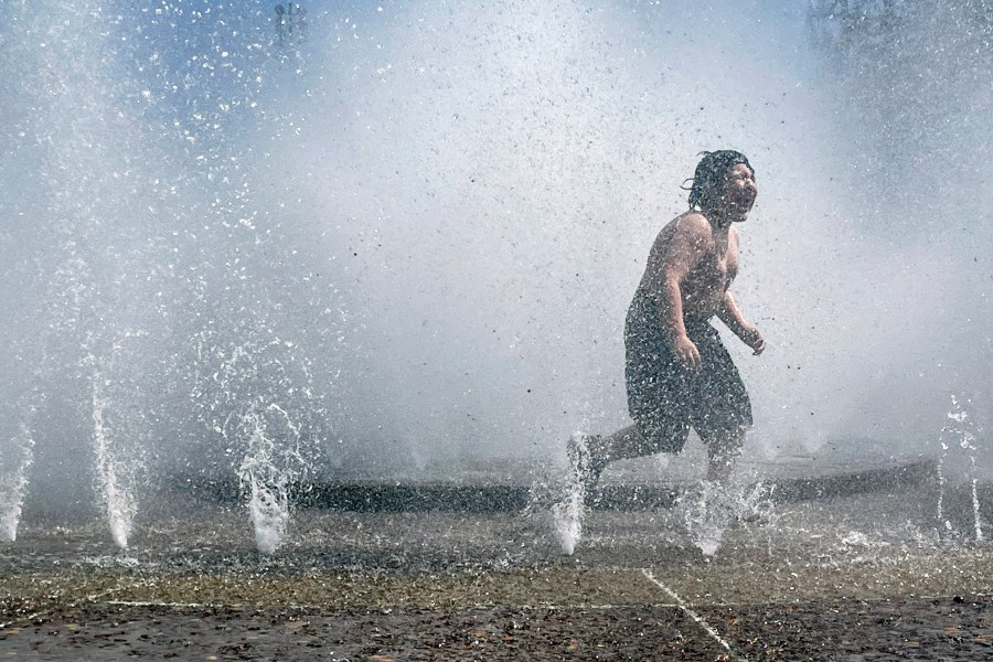 A child plays in a fountain to cool off in downtown Portland, Ore., Friday, May 12, 2023. An early May heat wave this weekend could surpass daily records in parts of the Pacific Northwest and worsen wildfires already burning in western Canada, a historically temperate region that has grappled with scorching summer temperatures and unprecedented wildfires fueled by climate change in recent years. (AP Photo/Claire Rush)