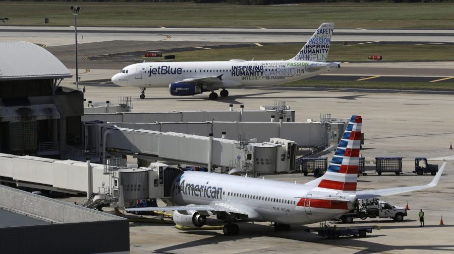 FILE - A JetBlue Airbus A320 taxis to a gate on Oct. 26, 2016, after landing, as an American Airlines jet is seen parked at its gate at Tampa International Airport in Tampa, Fla. The two airlines must abandon their partnership in the northeast United States, a federal judge in Boston ruled Friday, May 19, 2023, saying that the government proved that the deal reduces competition in the airline industry. (AP Photo/Chris O'Meara, File)