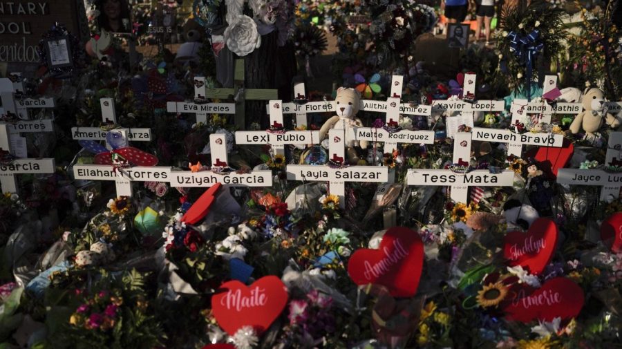 FILE - Flowers are piled around crosses with the names of the victims killed in a school shooting as people visit a memorial at Robb Elementary School to pay their respects May 31, 2022, in Uvalde, Texas. Families in Uvalde, Texas, are digging in for a new test of legal protections for the gun industry as they mark one year since the Robb Elementary School shooting. Both the U.S. government and gun manufacturers in recent years have reached large settlements following some of the nation's worst mass shootings. (AP Photo/Jae C. Hong, File)