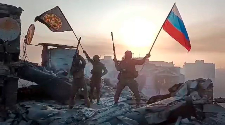 In this grab taken from video released by Prigozhin Press Service on Saturday, May 20, 2023, Yevgeny Prigozhin's Wagner Group military company members wave a Russian national and Wagner flag atop a damaged building in Bakhmut, Ukraine. The head of the Russian private army Wagner claims his forces have taken control of the city of Bakhmut after the longest and most grinding battle of the Russia-Ukraine war, but Ukrainian defense officials have denied it. In a video posted on Telegram, Prigozhin said the city came under complete Russian control at about midday Saturday. (Prigozhin Press Service via AP)