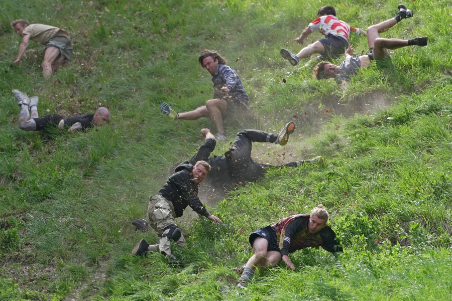 Participants compete in the men's downhill race during the Cheese Rolling contest at Cooper's Hill in Brockworth, Gloucestershire, Monday May 29, 2023. The Cooper's Hill Cheese-Rolling and Wake is an annual event where participants race down the 200-yard (180 m) long hill chasing a wheel of double gloucester cheese. (AP Photo/Kin Cheung)