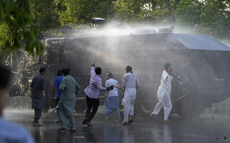 Supporters of Pakistan's former Prime Minister Imran Khan throw stones on a water-cannon