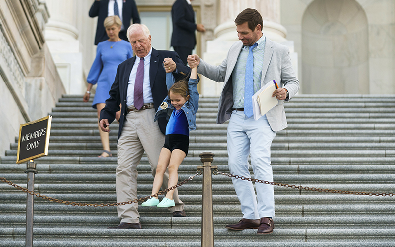 Reps. Mike Thompson and Eric Swalwell hold Swalwell’s daughter Kathryn in the air on the Capitol steps