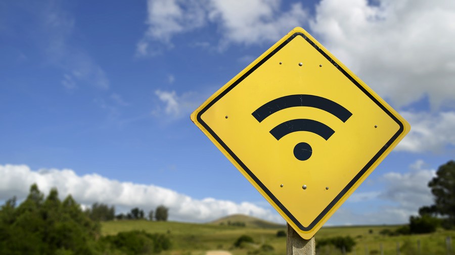 A wifi sign is seen against a rural environment with trees and grass