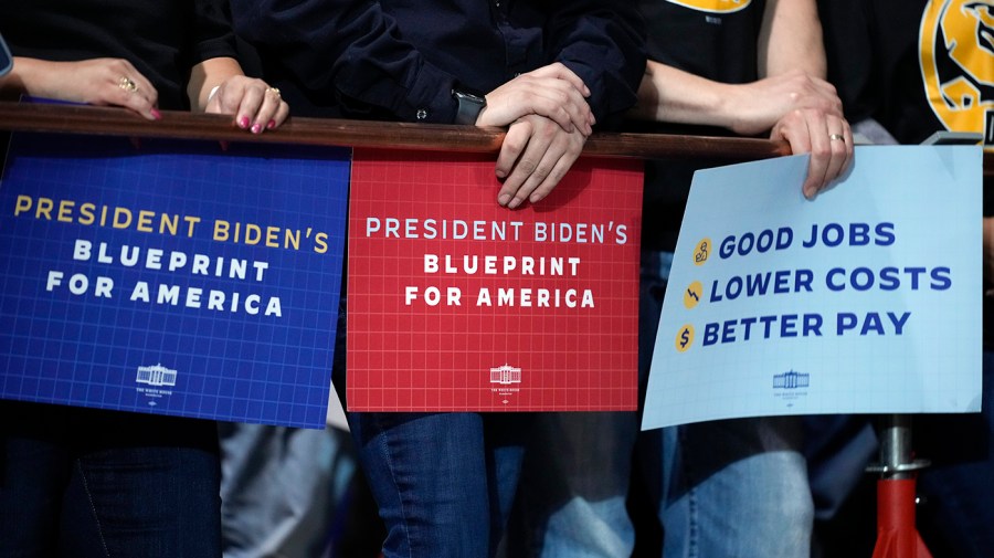 Union supporters of President Biden hold signs reading "President Biden's blueprint for America" and "Good jobs / lower costs / better pay"