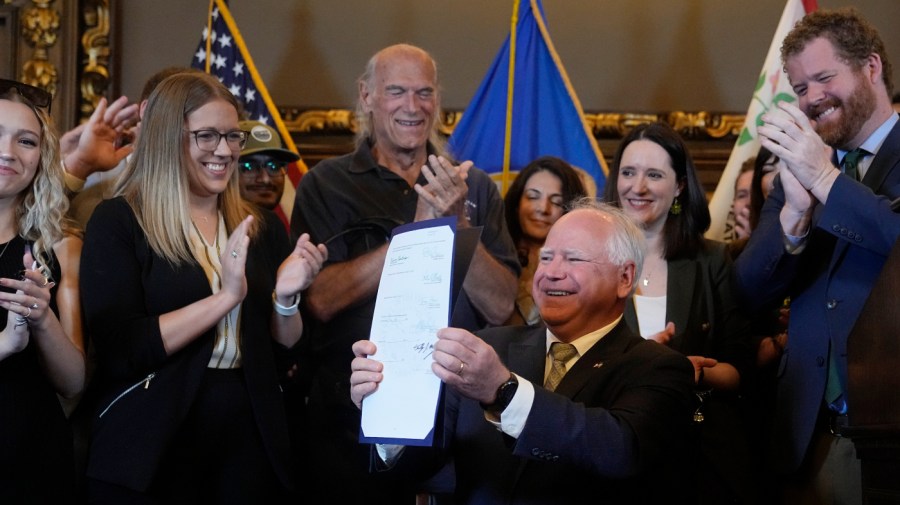 Former Minnesota Gov. Jesse Ventura (I), center, and others look on after Gov. Tim Walz (D) signed a bill to legalize recreational marijuana