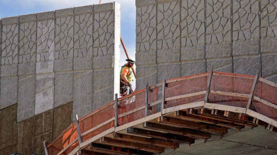 In this photo taken Oct. 4, 2018, a worker walks past a gap where tall panels are being erected on a wildlife bridge under construction over Interstate 90 on Snoqualmie Pass, Wash. The stretch of highway crossing the Cascade Mountains cuts through old growth forest and wetlands, creating a dangerous border for wildlife everything from an elk down to a small salamander. The new crossing gives animals in these mountains a safer option for crossing the road: They'll be able to go above it. (AP Photo/Elaine Thompson)