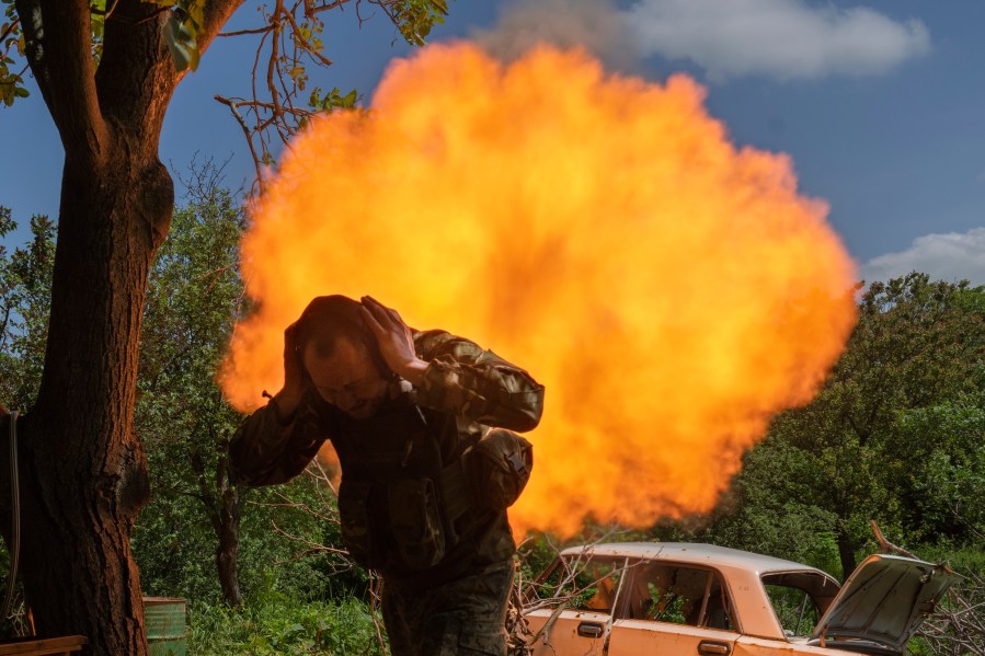 A Ukrainian soldier covers his ears while firing a mortar at Russian positions on the frontline near Bakhmut, Donetsk region, Ukraine, Monday, May 29, 2023. (AP Photo/Efrem Lukatsky)