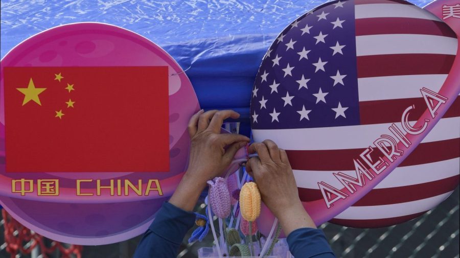 A vendor tights a flowers deco in between of the planets shaped of China and American flags on display at a store during a Spring Carnival in Beijing on May 13, 2023. Senior U.S. and Chinese diplomats held "candid and productive" talks in Beijing and agreed to keep open lines of communication to avoid tensions from spiraling into conflict, officials said Tuesday, June 6, 2023. (AP Photo/Andy Wong)