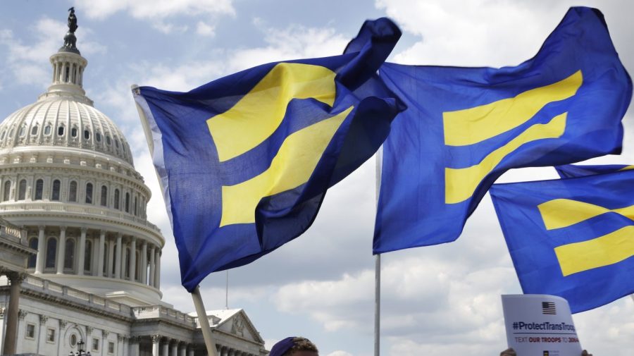 FILE - People with the Human Rights Campaign hold up "equality flags" during an event on Capitol Hill on July 26, 2017, in Washington, in support of transgender members of the military. The Human Rights Campaign declared a state of emergency for LGBTQ+ people in the U.S. on Tuesday, June 6, 2023, and a released “a guidebook for action” summarizing what it calls discriminatory laws in each state, along with “know your rights” information and health and safety resources. (AP Photo/Jacquelyn Martin, File)