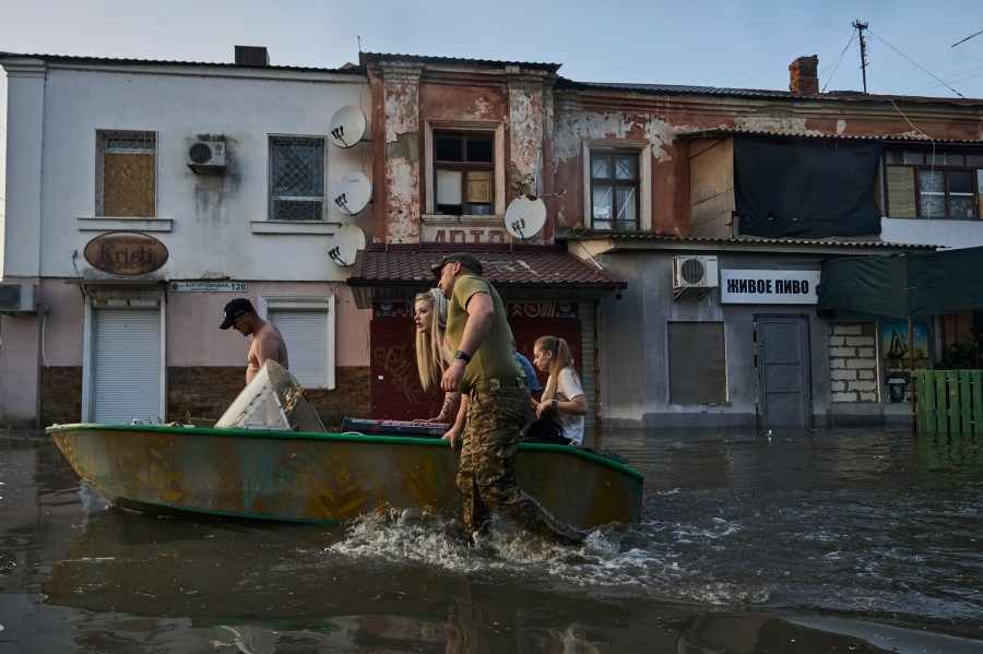 Rescue workers attempt to tow boats carrying residents being evacuated from a flooded neighborhood in Kherson, Ukraine, Tuesday, June 6, 2023. The wall of a major dam in a part of southern Ukraine has collapsed, triggering floods, endangering Europe's largest nuclear power plant and threatening drinking water supplies. (AP Photo/Libkos)