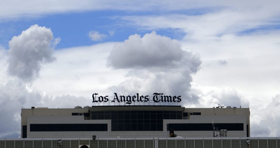 FILE - The Los Angeles Times building is seen behind a fence behind the Los Angeles International Airport, Friday, April 10, 2020. The Los Angeles Times on Wednesday, June 7, 2023, announced plans to cut 74 jobs due to economic challenges as the newspaper strives to transform itself into a digital media organization. (AP Photo/Richard Vogel, File)