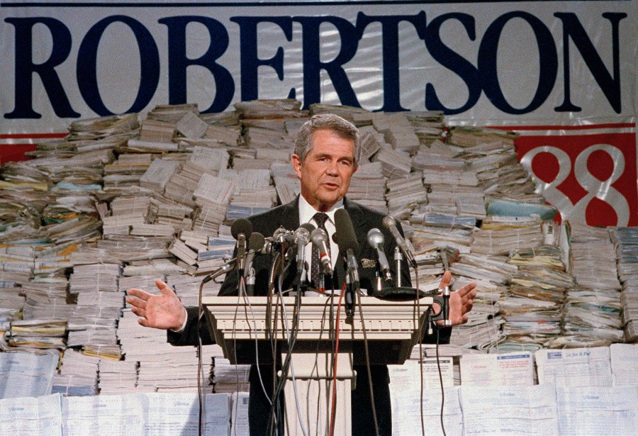 FILE - Pat Robertson, stands in front of stacks of signatures as he announced his intentions to collect a total of 7 million signatures during a news conference on Sept. 15, 1987 in Chesapeake, Va. Robertson, a religious broadcaster who turned a tiny Virginia station into the global Christian Broadcasting Network, tried a run for president and helped make religion central to Republican Party politics in America through his Christian Coalition, has died. He was 93. Robertson's death Thursday, June 8, 2023 was announced by his broadcasting network. (AP Photo/Steve Helber, file)