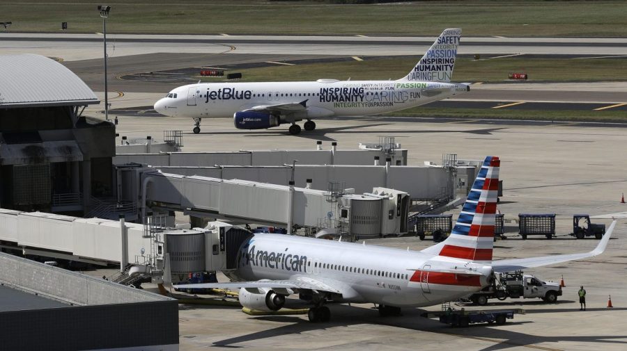 FILE - A JetBlue Airbus A320 taxis to a gate on Oct. 26, 2016, after landing, as an American Airlines jet is seen parked at its gate at Tampa International Airport in Tampa, Fla. The two airlines must abandon their partnership in the northeast United States, a federal judge in Boston ruled Friday, May 19, 2023, saying that the government proved that the deal reduces competition in the airline industry. (AP Photo/Chris O'Meara, File)