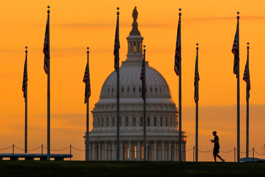 FILE - An early morning pedestrian is silhouetted against sunrise as he walks through the American flags on the National Mall with the U..S Capitol Building in the background in Washington Nov. 7, 2022. (AP Photo/J.David Ake, File)