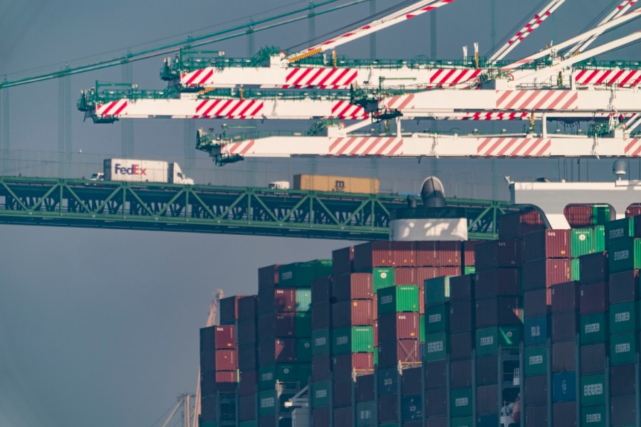 FILE - Transportation trucks cross the Vincent Thomas Bridge over the main channel as shipping containers are seen stacked on the Evergreen terminal at the Port of Los Angeles in San Pedro, Calif., Nov. 30, 2021.