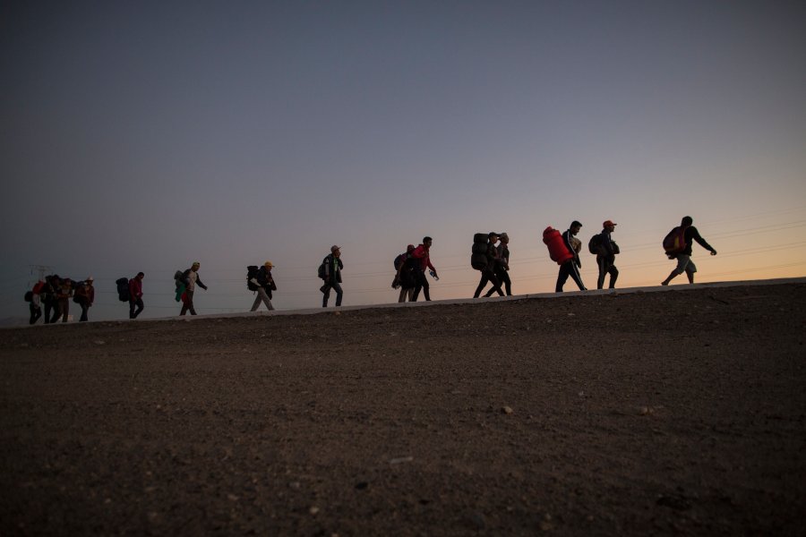 FILE - Central American migrants walk in the late afternoon as they leave Mexicali, Mexico, Nov. 20, 2018, on their way to Tijuana.